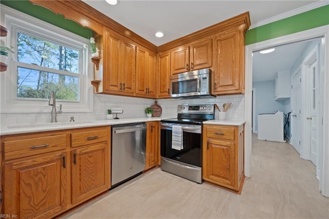 kitchen featuring stainless steel appliances, crown molding, backsplash, and sink