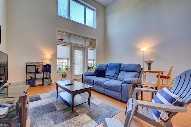 living room with wood-type flooring, a towering ceiling, and a wealth of natural light