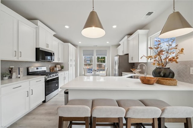 kitchen with appliances with stainless steel finishes, white cabinets, backsplash, and sink