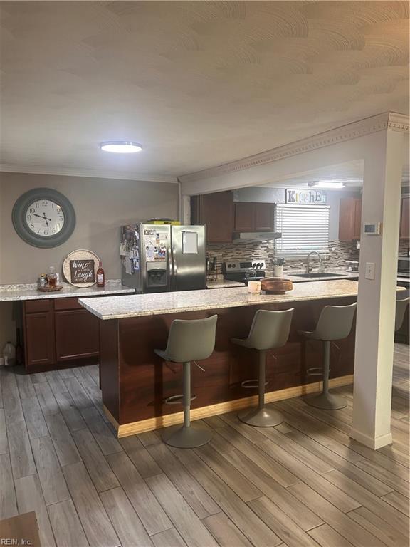 kitchen featuring a breakfast bar, appliances with stainless steel finishes, a center island, and ornamental molding