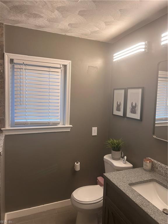 bathroom with toilet, vanity, tile patterned floors, and a wealth of natural light