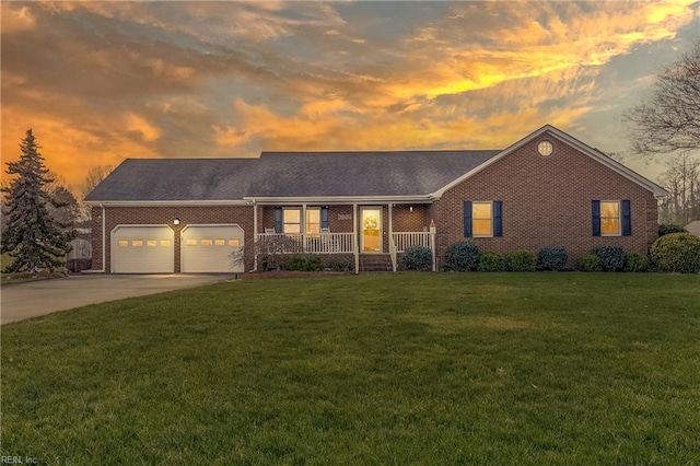 ranch-style house featuring a garage, a lawn, and covered porch