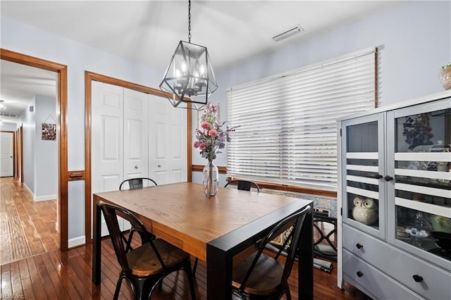 dining area featuring dark wood-type flooring and a notable chandelier