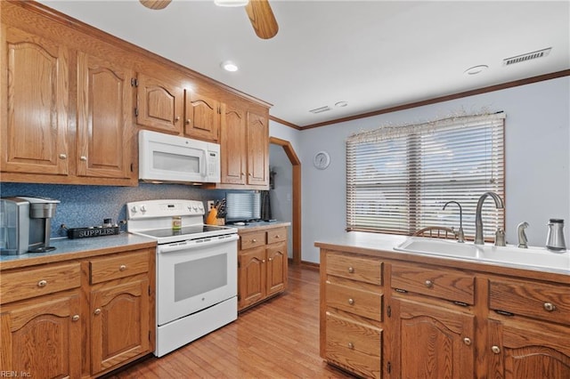 kitchen with tasteful backsplash, white appliances, sink, and light wood-type flooring