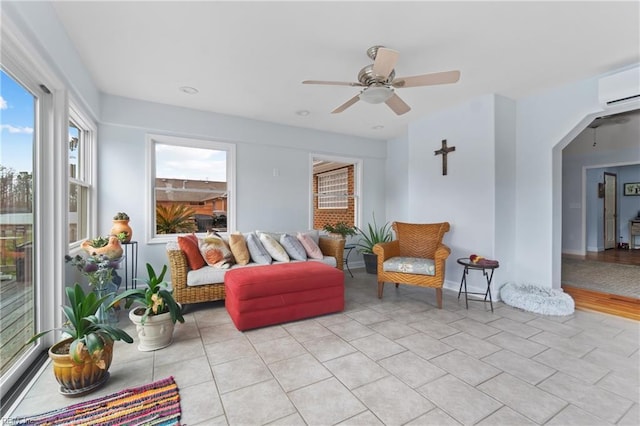 living room with a wall mounted AC, ceiling fan, and light tile patterned floors