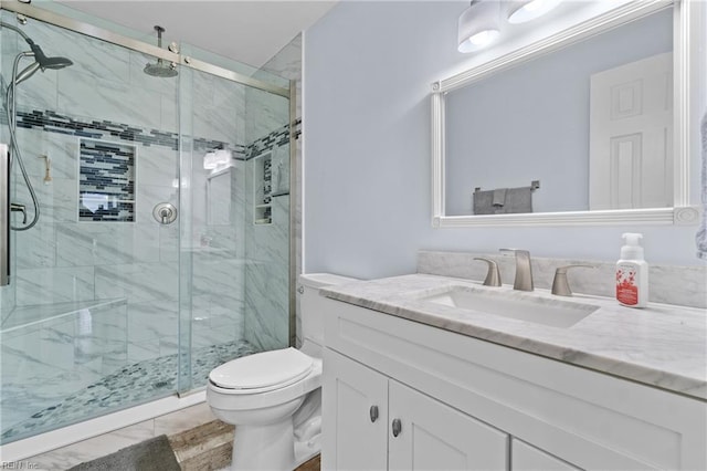 bathroom with vanity, a shower with door, and toilet