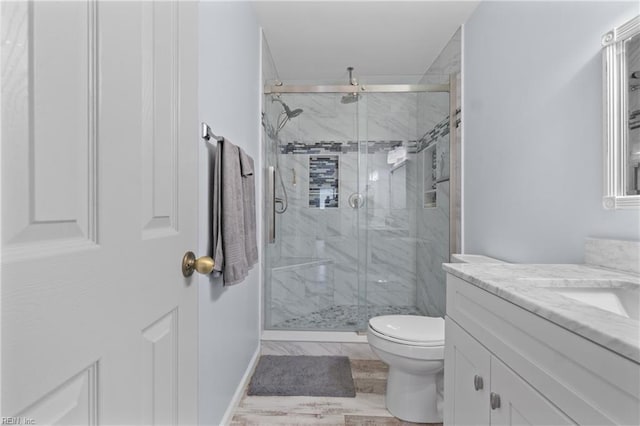 bathroom with vanity, a shower with shower door, and toilet