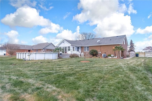 rear view of property featuring a yard and central AC