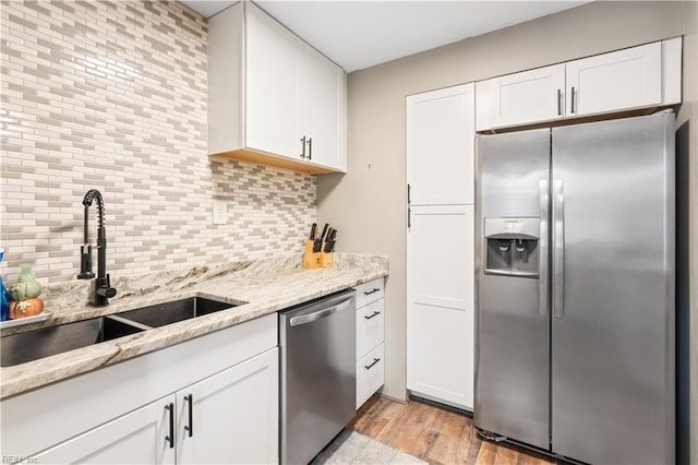 kitchen featuring white cabinets, decorative backsplash, appliances with stainless steel finishes, and sink