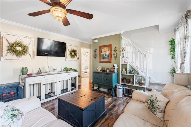 living room with dark wood-type flooring, ornamental molding, a wood stove, and ceiling fan