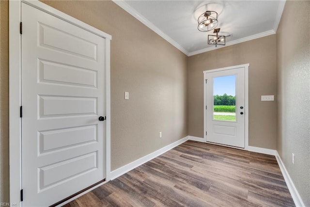 entryway featuring hardwood / wood-style flooring, ornamental molding, and a notable chandelier