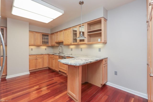 kitchen featuring light stone counters, light brown cabinetry, kitchen peninsula, and decorative light fixtures