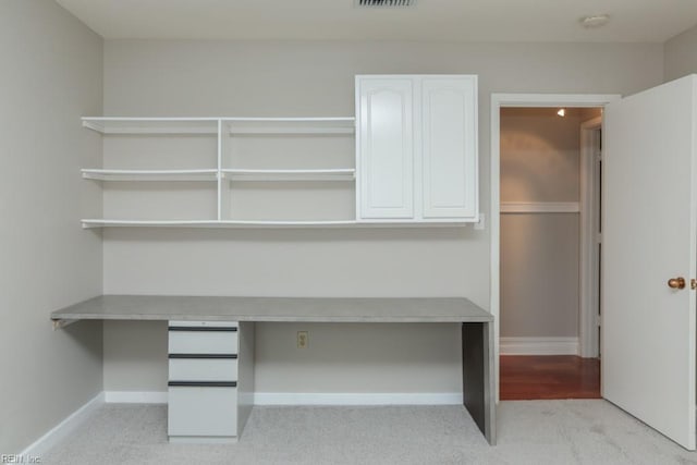 unfurnished office featuring light colored carpet and built in desk