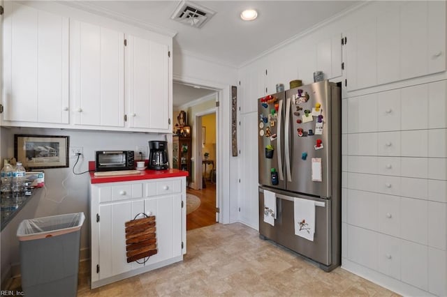 kitchen featuring ornamental molding, white cabinetry, and stainless steel refrigerator