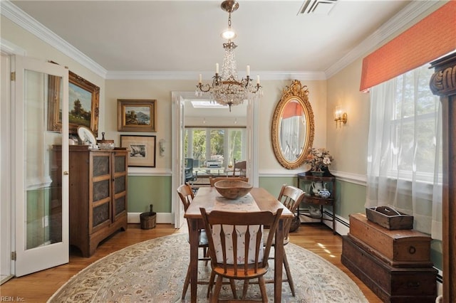 dining room with a chandelier, a baseboard radiator, ornamental molding, and light hardwood / wood-style floors