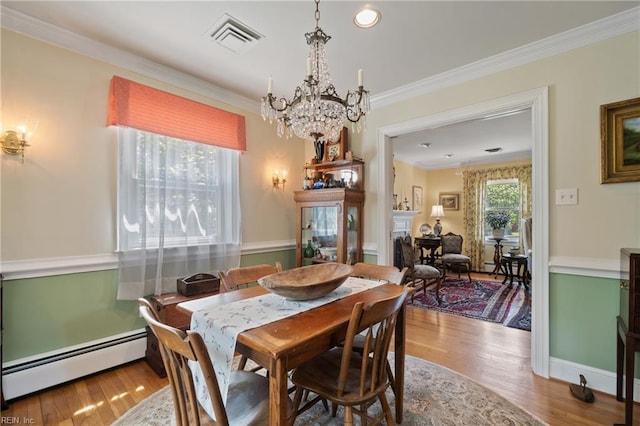 dining space with a baseboard radiator, ornamental molding, a chandelier, and light wood-type flooring