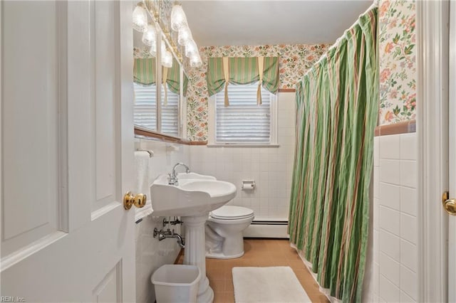 bathroom with toilet, baseboard heating, tile patterned flooring, and tile walls