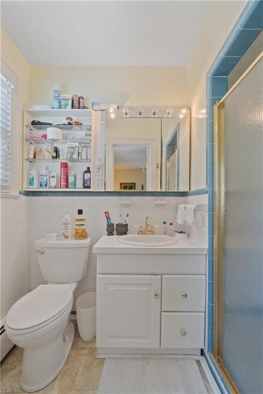 bathroom featuring toilet, tile walls, a shower with shower door, and vanity