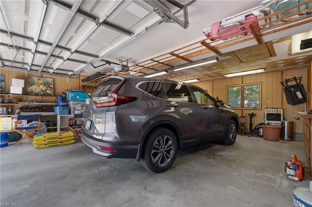 garage featuring a garage door opener and wooden walls