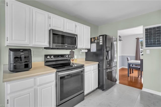 kitchen featuring light tile patterned flooring, appliances with stainless steel finishes, and white cabinetry