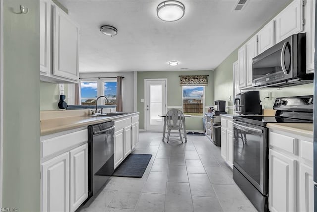 kitchen with sink, stainless steel electric stove, black dishwasher, and white cabinetry