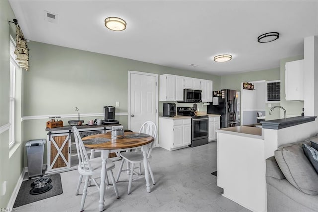 kitchen featuring kitchen peninsula, appliances with stainless steel finishes, sink, and white cabinetry