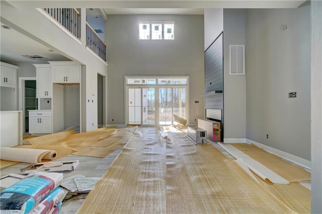 unfurnished living room with light hardwood / wood-style flooring and a towering ceiling