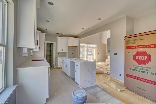 kitchen with light wood-type flooring, white cabinetry, and a center island