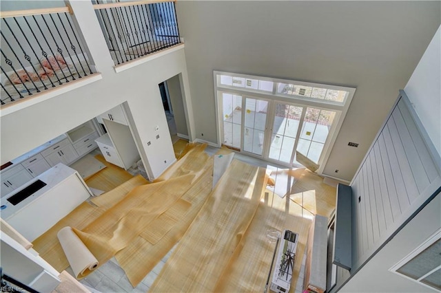 living room with french doors, a towering ceiling, and light hardwood / wood-style floors