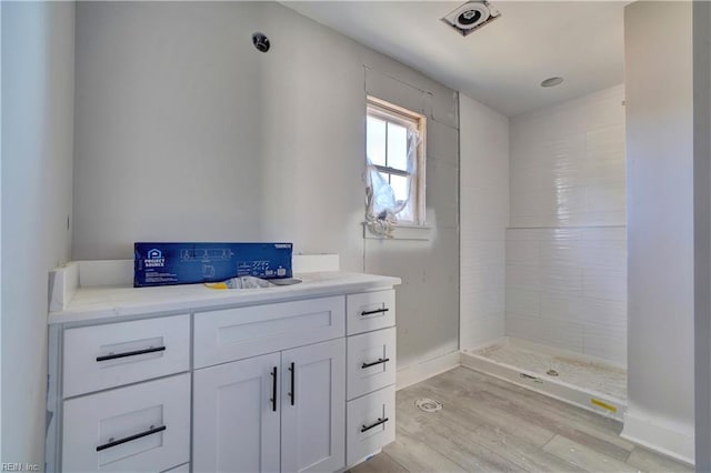 bathroom featuring hardwood / wood-style floors, tiled shower, and vanity