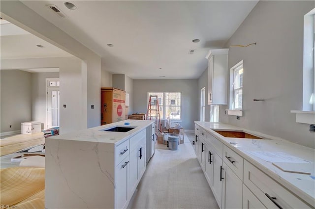 kitchen featuring light stone countertops, white cabinetry, and a center island