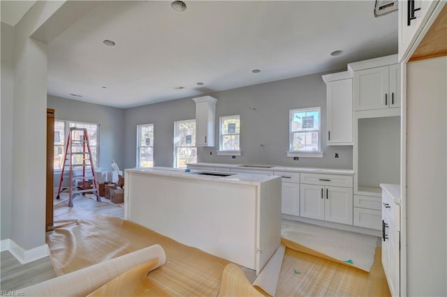 kitchen with a kitchen island, light hardwood / wood-style floors, and white cabinets