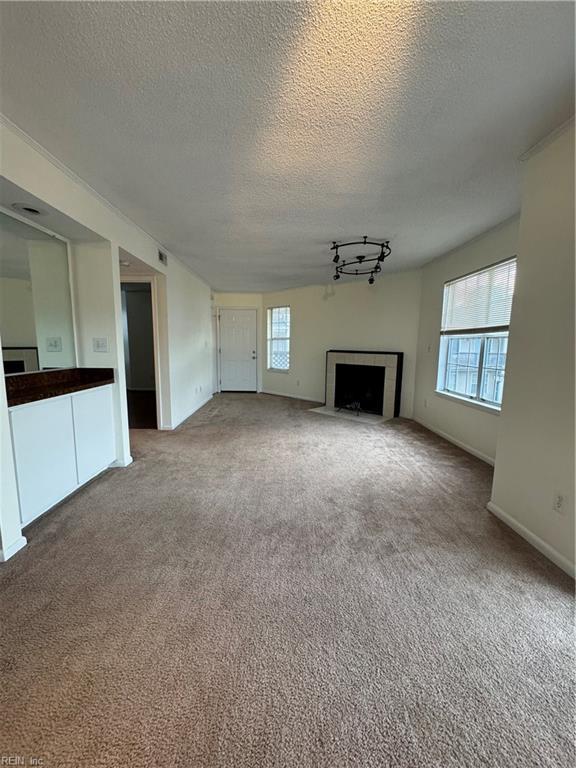 unfurnished living room featuring a textured ceiling, carpet, and track lighting