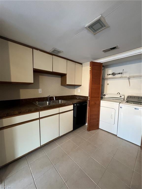 kitchen featuring light tile patterned floors, sink, black dishwasher, and separate washer and dryer