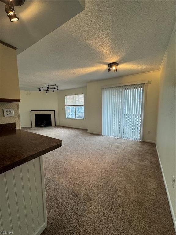 unfurnished living room featuring carpet floors, a textured ceiling, and rail lighting