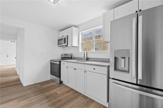 kitchen featuring sink, white cabinetry, light hardwood / wood-style flooring, and stainless steel appliances