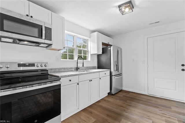 kitchen featuring sink, hardwood / wood-style floors, white cabinets, and stainless steel appliances