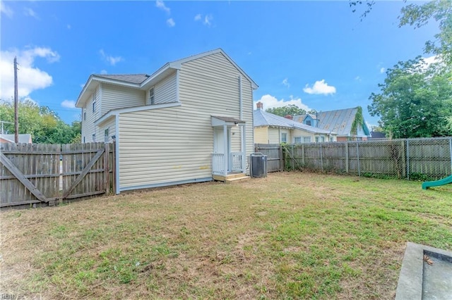 rear view of house with cooling unit and a yard