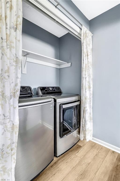 clothes washing area featuring independent washer and dryer and light hardwood / wood-style floors