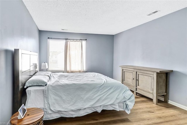 bedroom featuring light hardwood / wood-style flooring and a textured ceiling