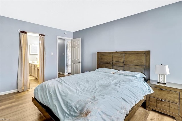 bedroom featuring connected bathroom and light hardwood / wood-style flooring