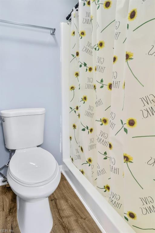 bathroom with hardwood / wood-style flooring, toilet, and a shower with shower curtain