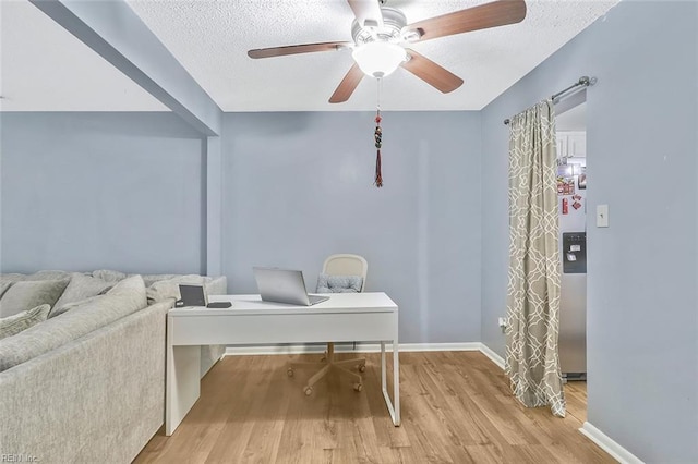 home office with ceiling fan, light hardwood / wood-style floors, and a textured ceiling