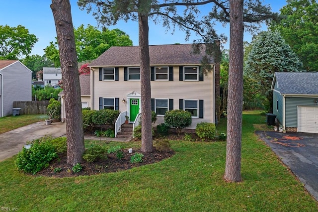 colonial house with a front yard, a garage, and cooling unit