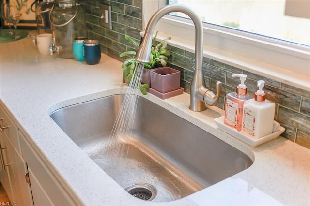 room details with backsplash, sink, and light stone counters