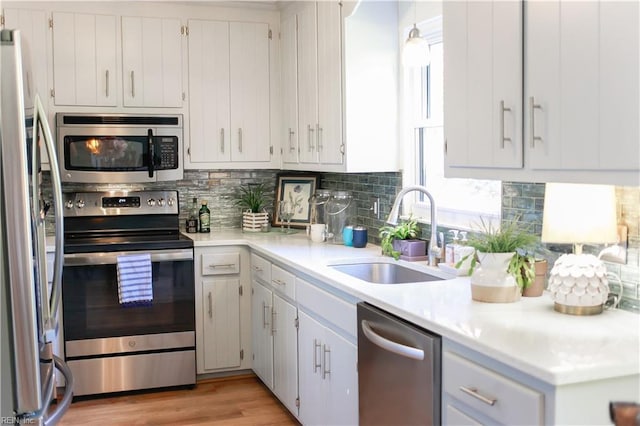 kitchen featuring stainless steel appliances, backsplash, white cabinetry, and sink