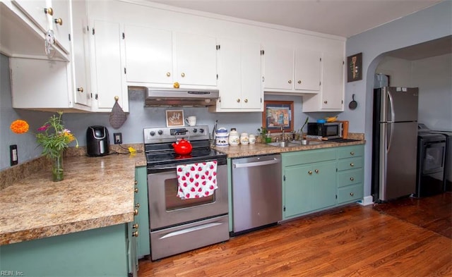 kitchen featuring stainless steel appliances, dark wood-type flooring, white cabinets, washer / clothes dryer, and sink