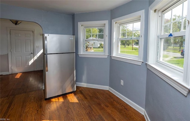 kitchen with dark hardwood / wood-style flooring, a healthy amount of sunlight, and stainless steel refrigerator