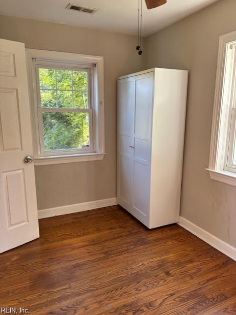 unfurnished bedroom featuring ceiling fan, dark hardwood / wood-style flooring, and multiple windows