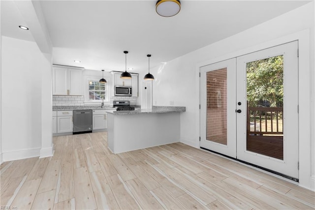 kitchen featuring white cabinetry, kitchen peninsula, stainless steel appliances, decorative backsplash, and french doors